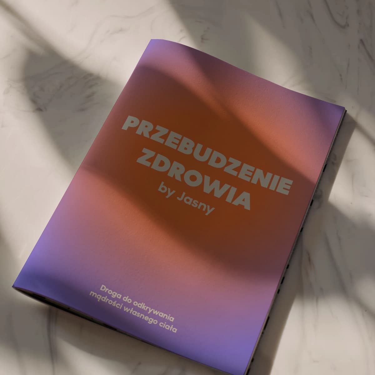 Okładka ebooka Przebudzenie zdrowia by Jasny w fioletowo-pomarańczowym gradiencie, leżąca na marmurowym blacie.